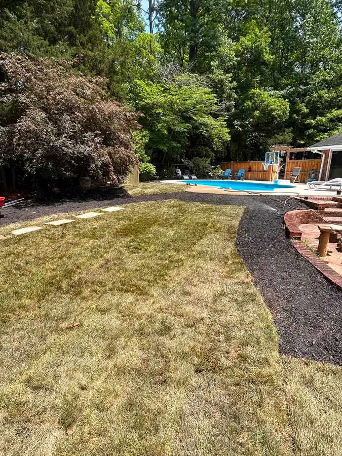 Fresh sod lawn, mulch beds, and flagstone steppers wrapping a backyard pool