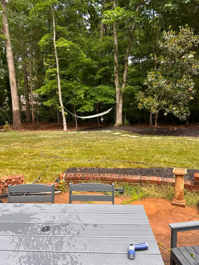 Backyard with a raised brick planter, mulch beds, and lawn viewed from a patio
