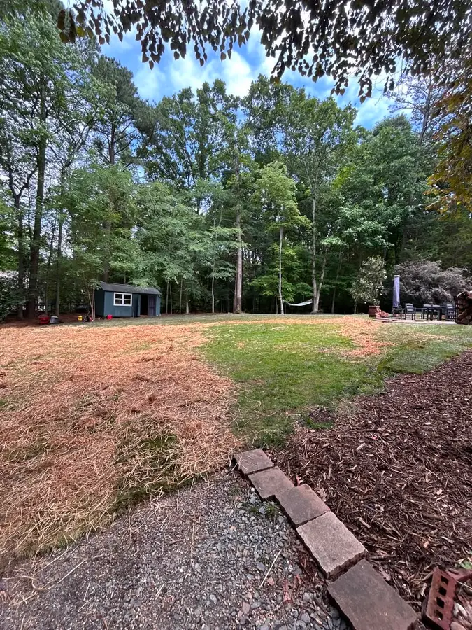 Cleared and mulched wooded backyard with an open lawn and garden shed