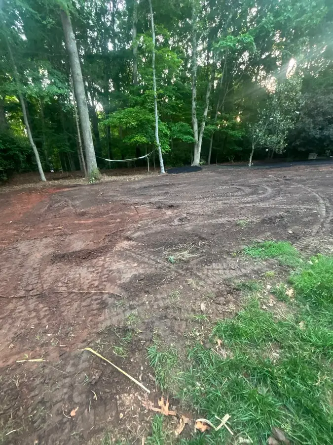 Freshly graded backyard soil prepared for new sod, with tractor tracks